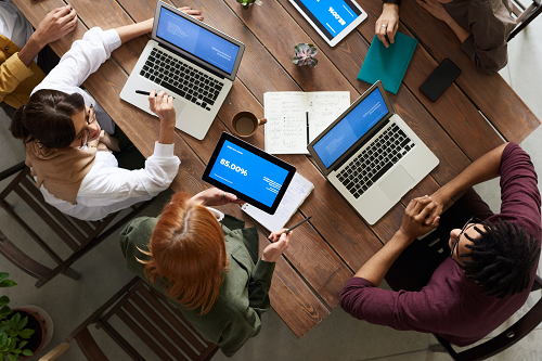 Employees in a meeting room with laptop computers.