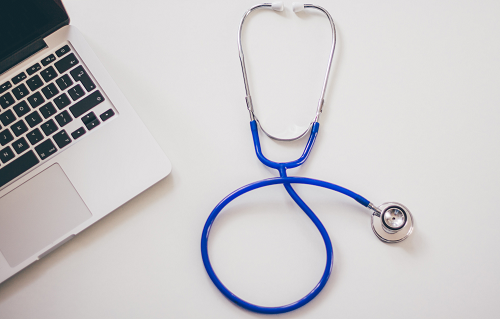 A stethoscope next to a computer.