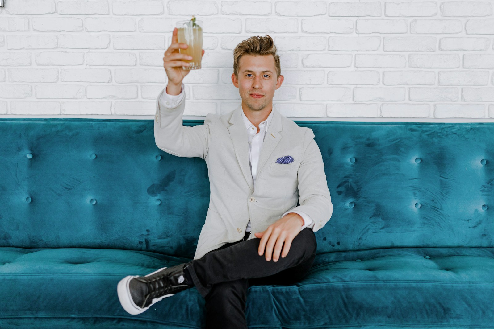 benefits consultant man in gray blazer raising drinking glass while sitting on sofa