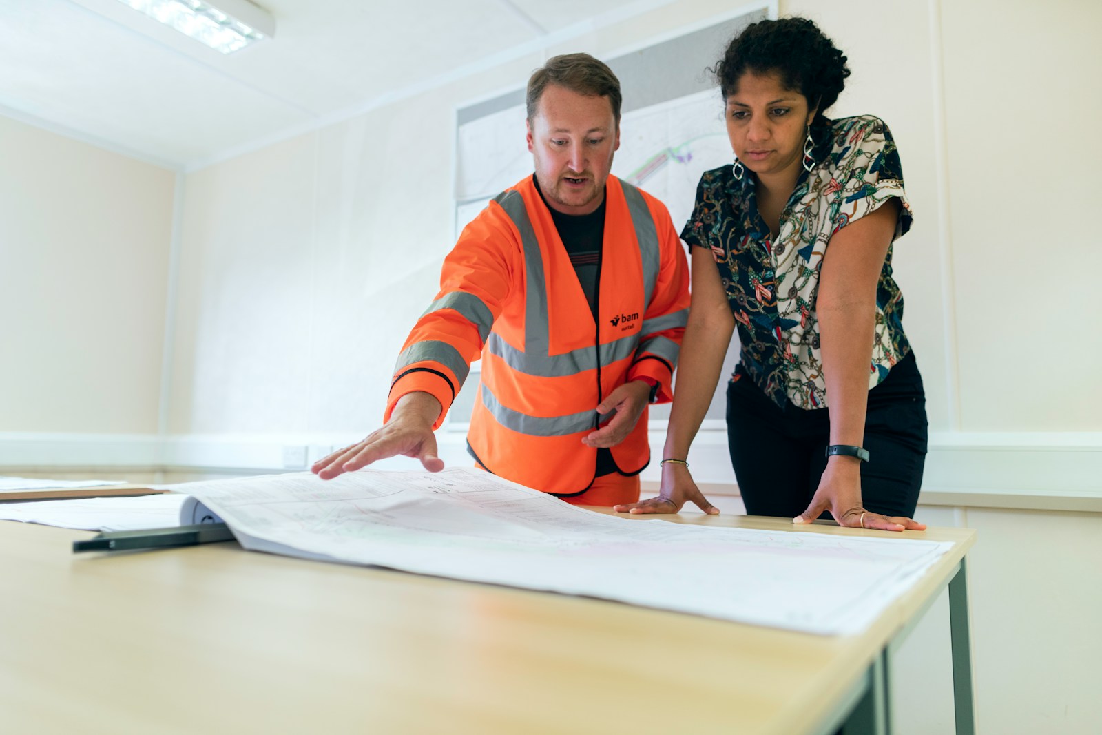 man in orange and white striped polo shirt beside woman in black and white floral dress demonstrating risk assessment