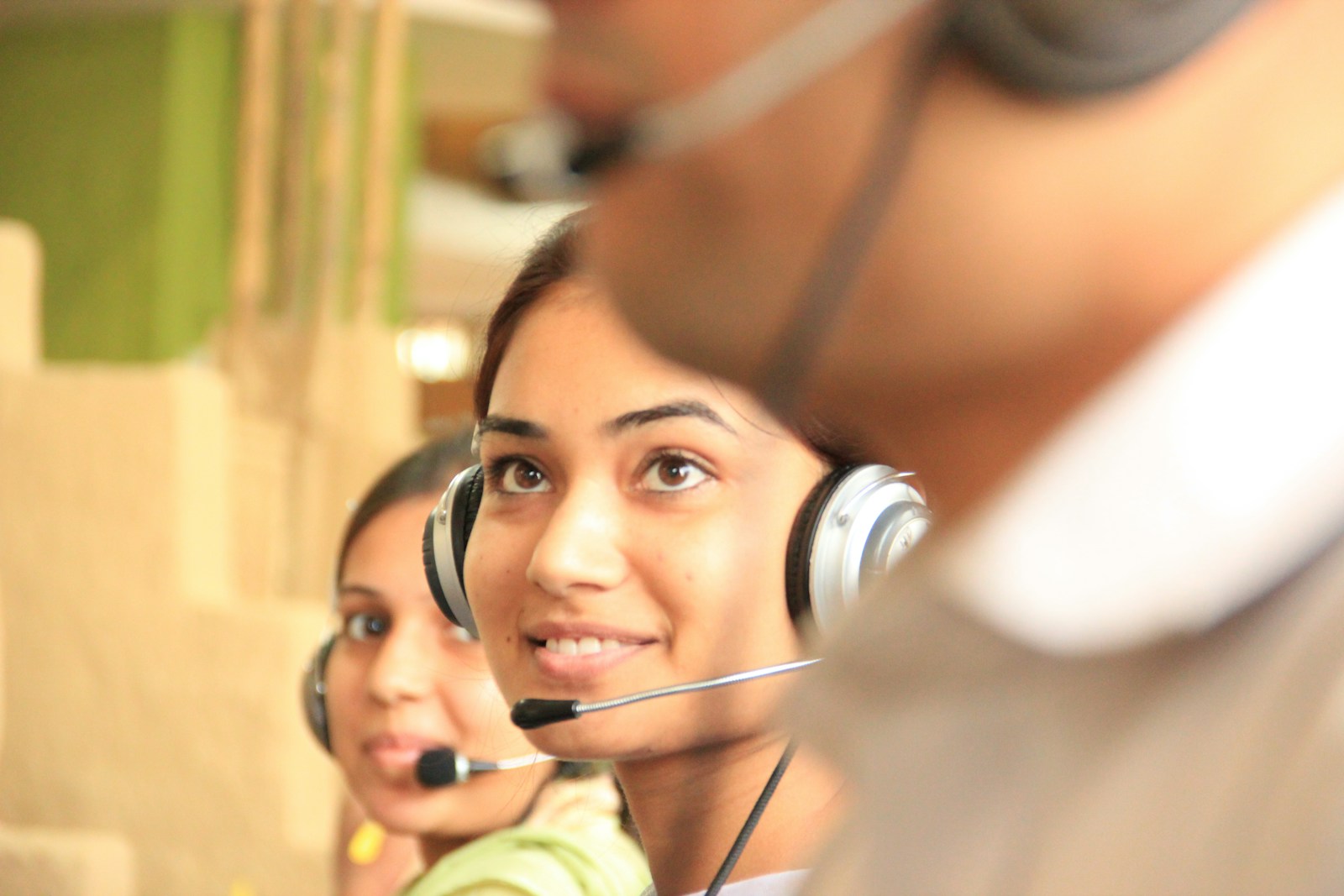 woman in black headphones holding black and silver headphones showing happiness which results in lower employee turnover