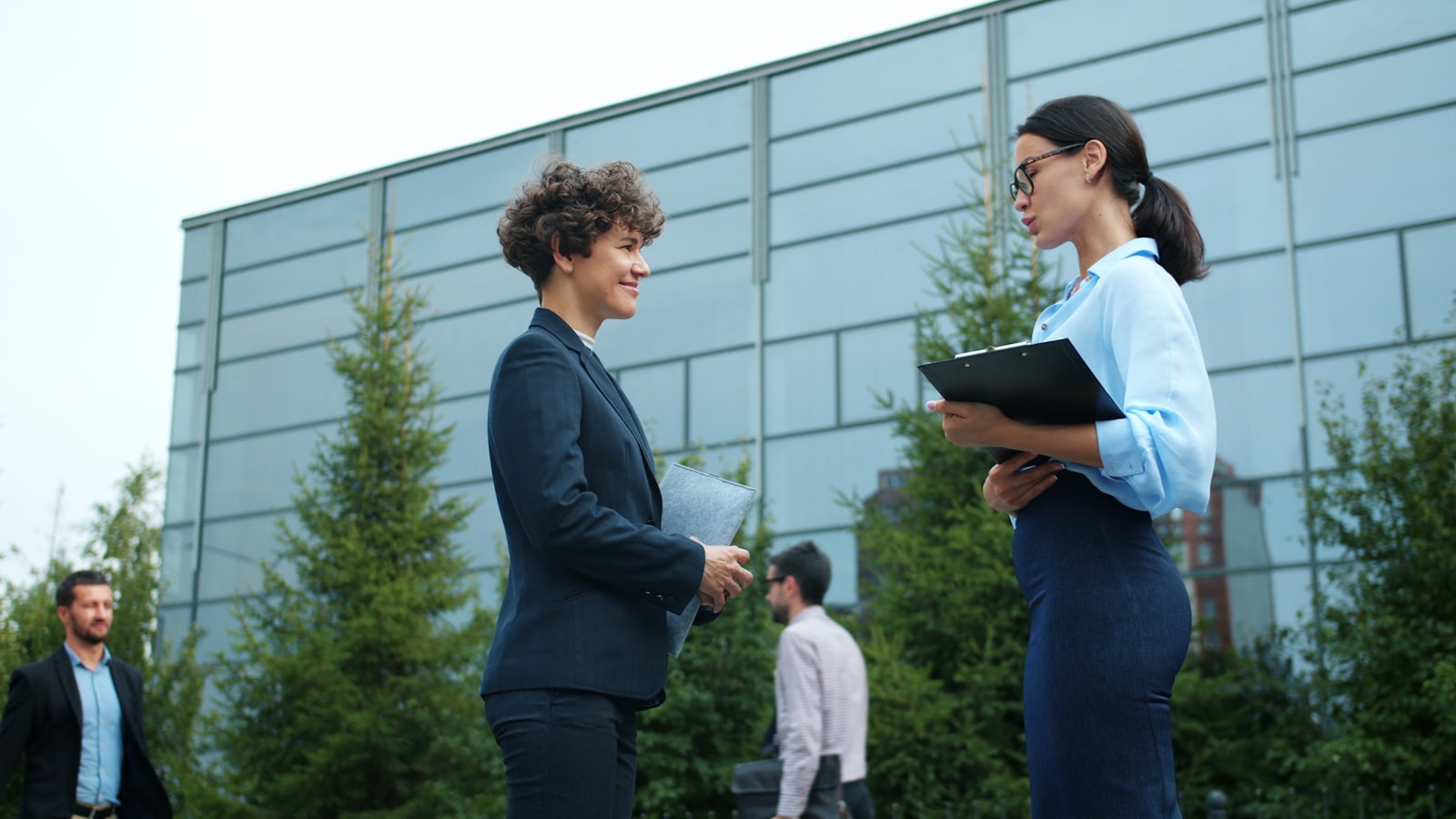 Two businesswomen talking outside modern building